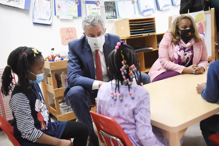 Wearing masks, Mayor Bill de Blasio and Chancellor Meisha Porter visit a group of young girls sitting at a table inside a preschool in Flatbush.